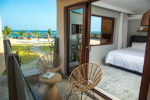a bedroom with a bed and chairs on a balcony at Sandy Shore Beach Apartments - Karibu Quarters in Kikambala