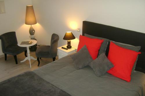 a bedroom with a bed with red and gray pillows at Gîte & Chambres d'Hôtes - Le Petit Bali in Saint-Pandelon