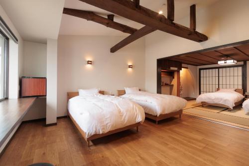 two beds in a large room with wooden floors at 伊根の舟屋 樹 Funaya Inn Tatsuki , Ine in Kameshima