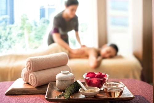 a table with a tray of towels and a man in bed at Makati Shangri-La, Manila in Manila