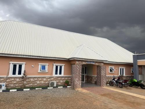 a house with a white roof and some motorcycles at Hanover Hotels Suleja in Tunga Bai