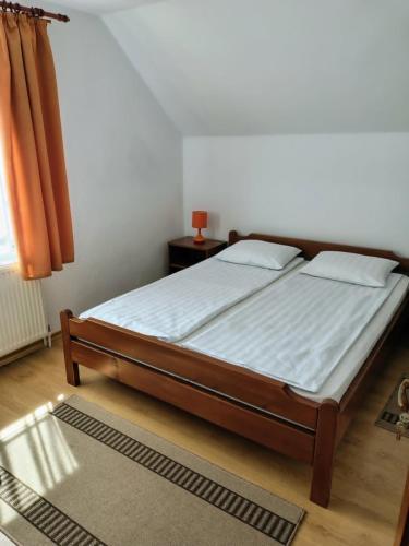 a bed in a bedroom with a white mattress at Akácpatak Vendégház in Lupeni