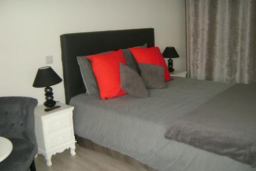 a bedroom with a bed with red pillows and a chair at Gîte & Chambres d'Hôtes - Le Petit Bali in Saint-Pandelon