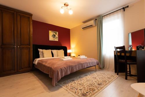 a bedroom with a bed with red walls and a window at Aleko Apartments City Center in Veliko Tŭrnovo
