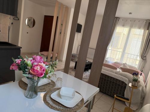 a living room with a table with a vase of flowers at Bienvenue au Nid Rosé in Montereau-Fault-Yonne