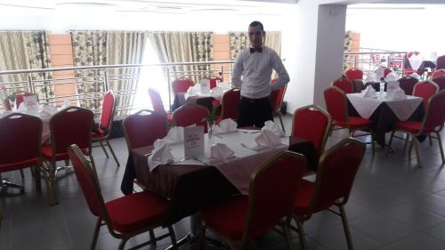 a man standing in a room with tables and chairs at Hotel Arena Fes in Fès