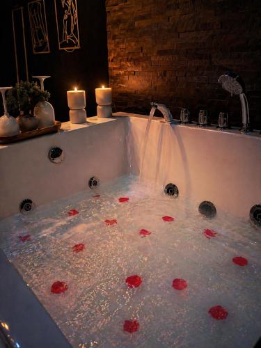 a bath tub with red flowers in the water at Love Room balnéo double & sauna Privés - Nuit d'exception in Briord