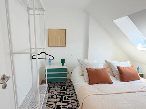 a white room with a bed with orange and white pillows at TRIPLEX 2 chambres Cosy à MONS in Mons
