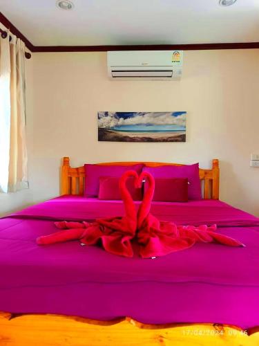 a bed with a red ribbon on it at นงนุช โฮมสเตย์ & รีสอร์ท บุรีรัมย์ in Buriram