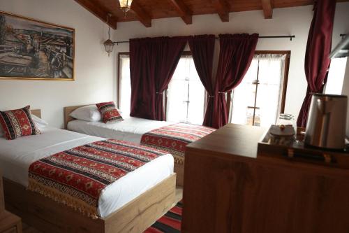 a hotel room with two beds with red curtains at Hotel Ari Old Town in Gjakove