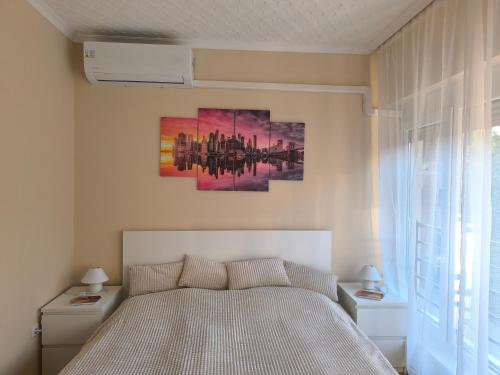 a bedroom with a bed and a painting on the wall at FAVORIT CENTRUM Apartman in Kaposvár