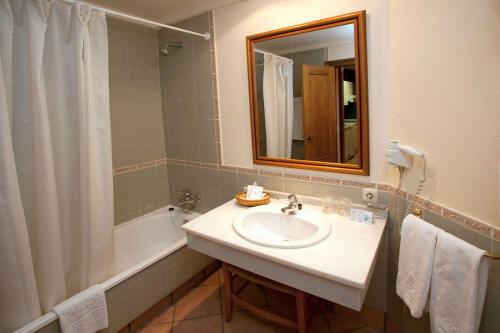 a bathroom with a sink and a tub and a mirror at Hotel Apartamentos Trevenque in Sierra Nevada