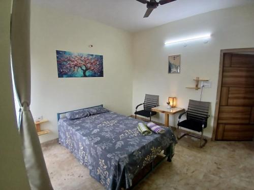a bedroom with a bed and two chairs and a table at O2 Homes in Guwahati