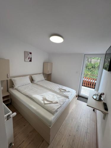 a white bedroom with a bed and a window at Domeniul La Mosie in Slimnic
