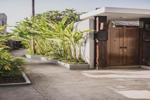a building with a wooden door and some plants at Sanora Villa Sanur by Ini Vie Hospitality in Sanur