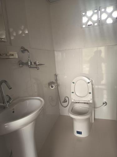 a white bathroom with a toilet and a sink at hotel lakema in Pokhara
