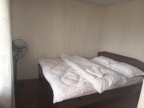 an unmade bed with white sheets and a fan at hotel lakema in Pokhara