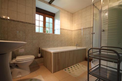 a bathroom with a tub and a toilet and a sink at Holiday home Le Pressoir in Domfront