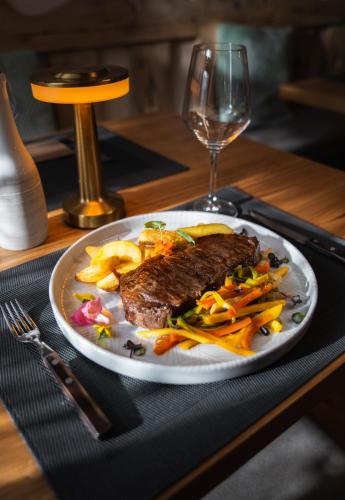 a plate of steak and vegetables and a glass of wine at Bed & Breakfast LakeBled House in Bled