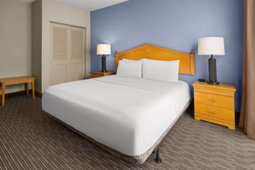 a bedroom with a white bed and a blue wall at Days Hotel by Wyndham Toms River Jersey Shore in Toms River