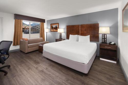 a hotel room with a large bed and a chair at Baymont by Wyndham Durango in Durango