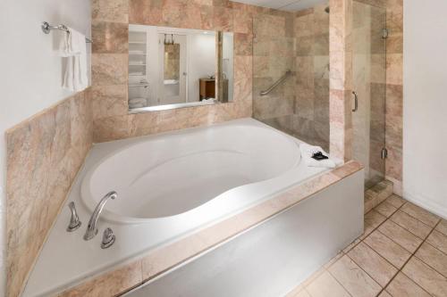 a large white tub in a bathroom with a mirror at Baymont by Wyndham Durango in Durango