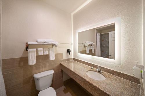 a bathroom with a toilet and a sink and a mirror at Baymont by Wyndham Texas City in Texas City