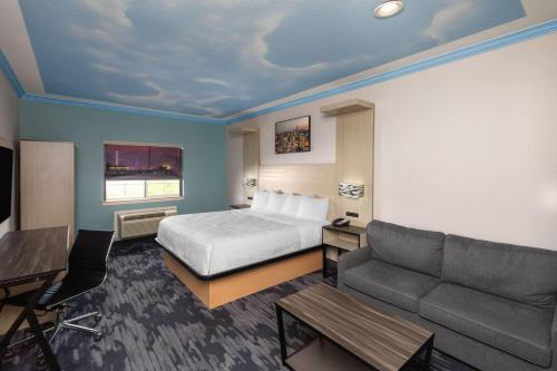 a hotel room with a bed and a couch at Baymont by Wyndham Texas City in Texas City