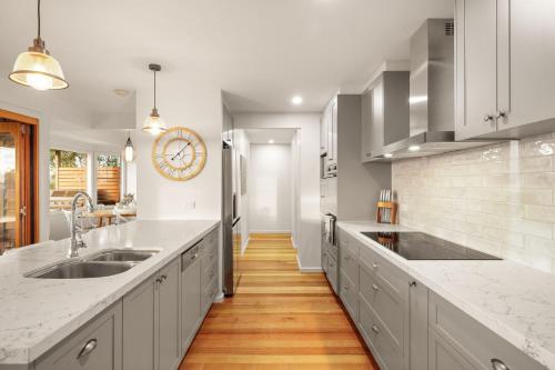 a kitchen with white cabinets and a wooden floor at Seaview Escape in Ventnor