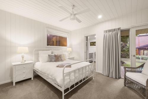 a white bedroom with a bed and a chair at Seaview Escape in Ventnor
