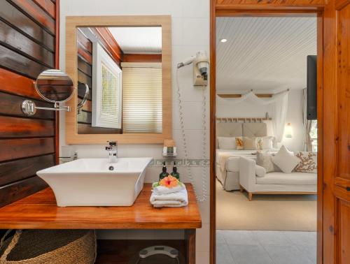 a bathroom with a sink and a bedroom at Acajou Beach Resort in Baie Sainte Anne