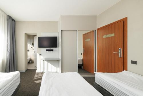 a hotel room with two beds and a television at Jūratės B&B Namai in Karmėlava