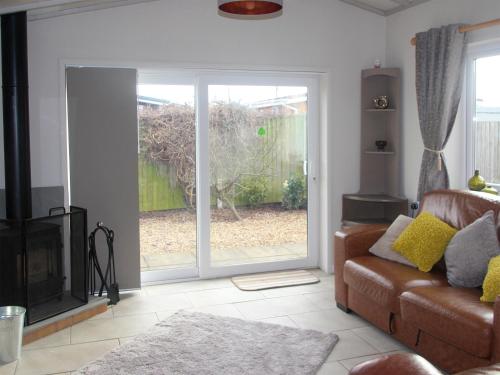 a living room with a couch and a sliding glass door at Sandy Creek Cottage - E5349A in Anderby