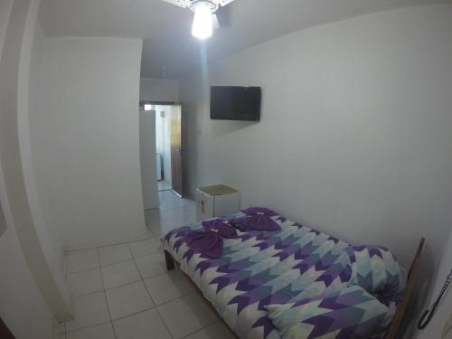 a bedroom with a bed and a tv on the wall at Pousada do Primo in Capão da Canoa
