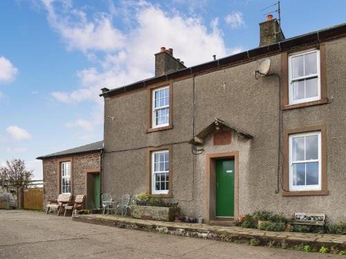 a brick house with a green door at Harebeck Cottage in Gosforth
