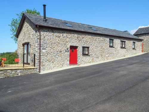 a stone building with a red door on a street at Parlwr Godro - Uk41513 in Llanfair Clydogau