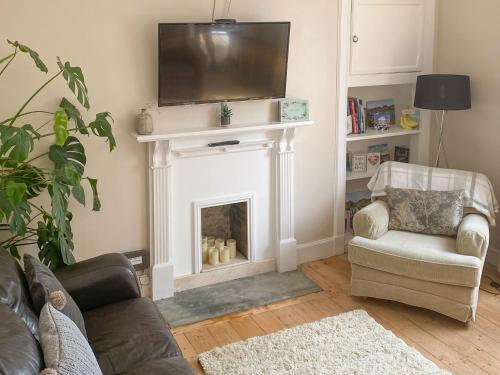 a living room with a fireplace with a television above it at The Wee Cottage - Uk42919 in Dunfermline