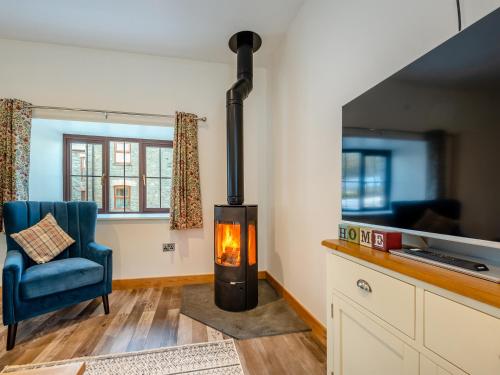 a wood stove in a living room with a blue chair at Ty Gwair - Uk41512 in Lampeter