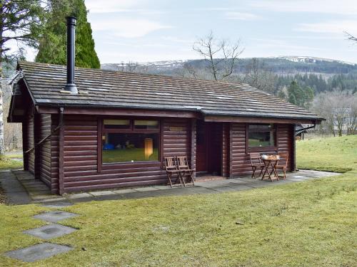 a log cabin with a table and chairs in a field at Forest View in Strathyre