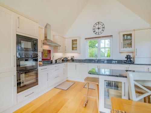 a kitchen with white cabinets and a clock on the wall at Twill Lodge - 4 Swandown in Cudworth