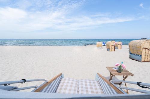 a view of the beach with chairs and a table at Schlafstrandkorb Nr 8 in Timmendorfer Strand