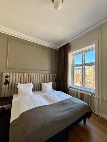 a bedroom with a large bed and two windows at Hotel Sct. Thomas in Copenhagen