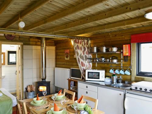 a kitchen with a table with chairs and a stove at Kestrel Cabin - Uk1246 in Westward