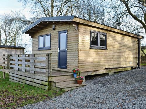 a wooden tiny house with a porch and a fence at Kestrel Cabin - Uk1246 in Westward