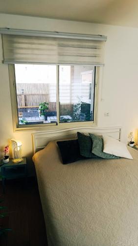ein Schlafzimmer mit Fenster und einem Bett mit Kissen in der Unterkunft אלת המדברGoddess of the desert in Beʼer Ora