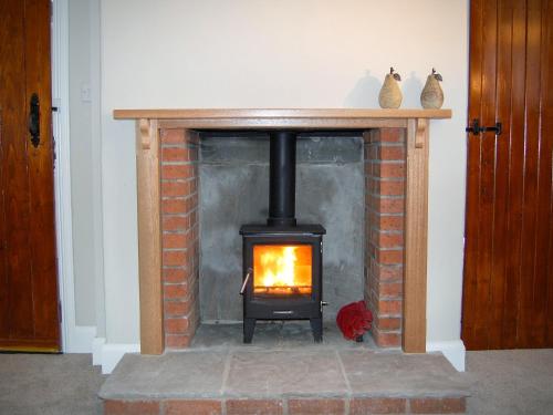 a brick fireplace with a stove in a room at Summergate Cottage in Annan