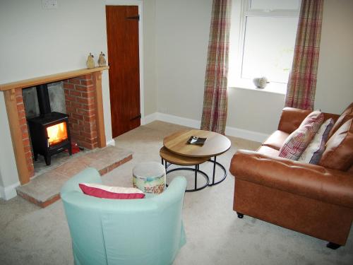 a living room with a couch and a table and a fireplace at Summergate Cottage in Annan
