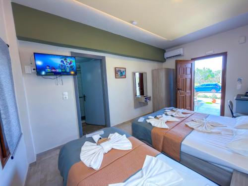 two beds in a hotel room with a tv on the wall at Elafonisi Paradise with Parking, WiFi, - Walking Distance to the Beach in Elafonisi
