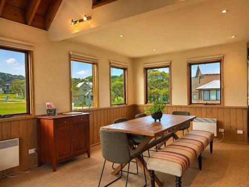 a dining room with a table and chairs and windows at Dragonfly Chalet in Dinner Plain