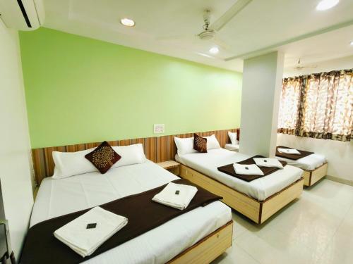 two beds in a room with two tables and towels at Sai Tara Residency in Shirdi